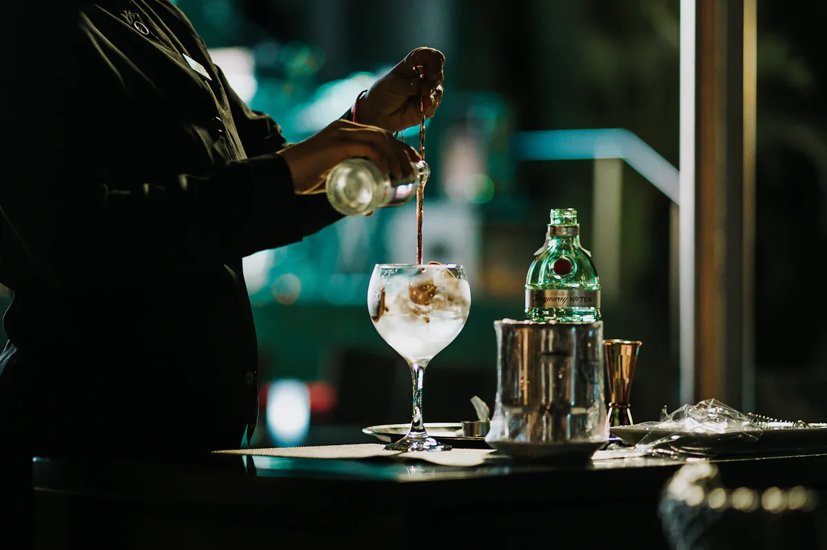 Bartender pouring a cocktail behind the bar