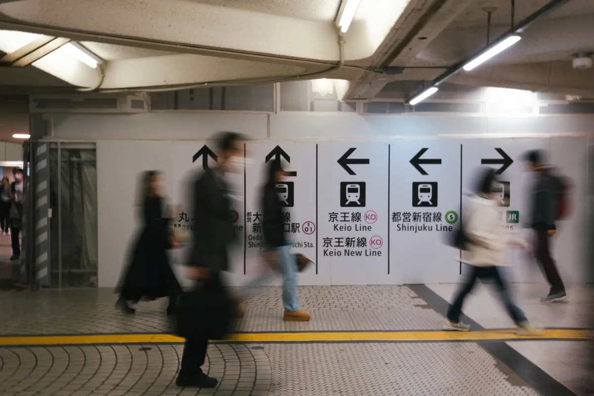 Inside Shinjuku Station  -  six route information boards over a busy concourse
