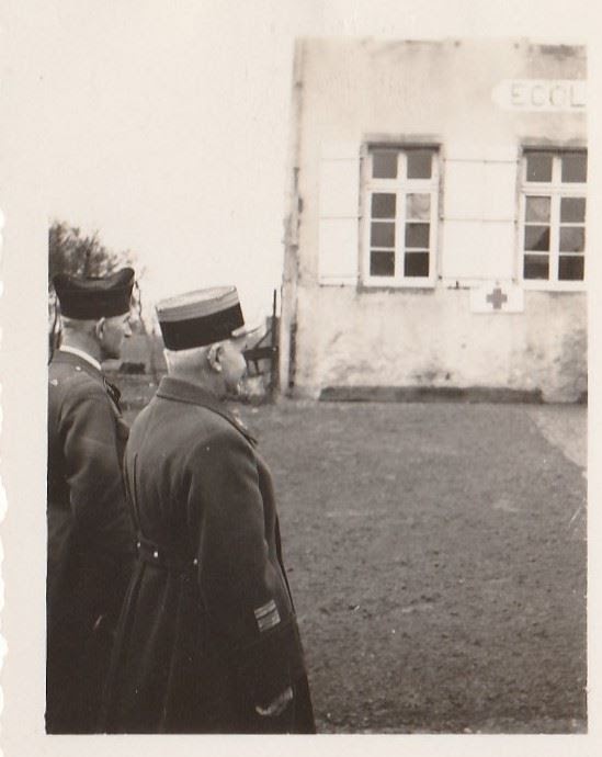 Deux officiers devant l'école transformée en infirmerie, croix rouge visible sur la façade